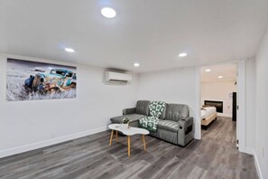 A modern living room with a grey sofa, a small white table, and a painting on the wall. - Spacious 4BR/2BA Home @Seattle | Ping Pong & BBQ (Seattle)