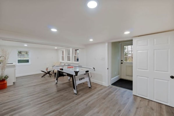 A spacious room with a foosball table, wooden flooring, a door, and a window. - Spacious 4BR/2BA Home @Seattle | Ping Pong & BBQ (Seattle)