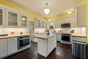 A modern kitchen with white cabinetry, a central island, and a coffee bar sign. - Spacious 4BR/2BA Home @Seattle | Ping Pong & BBQ (Seattle)