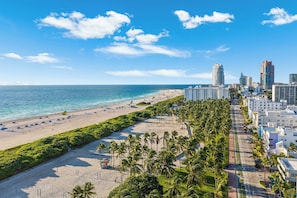 Un paisaje urbano costero con playa, palmeras y edificios altos.