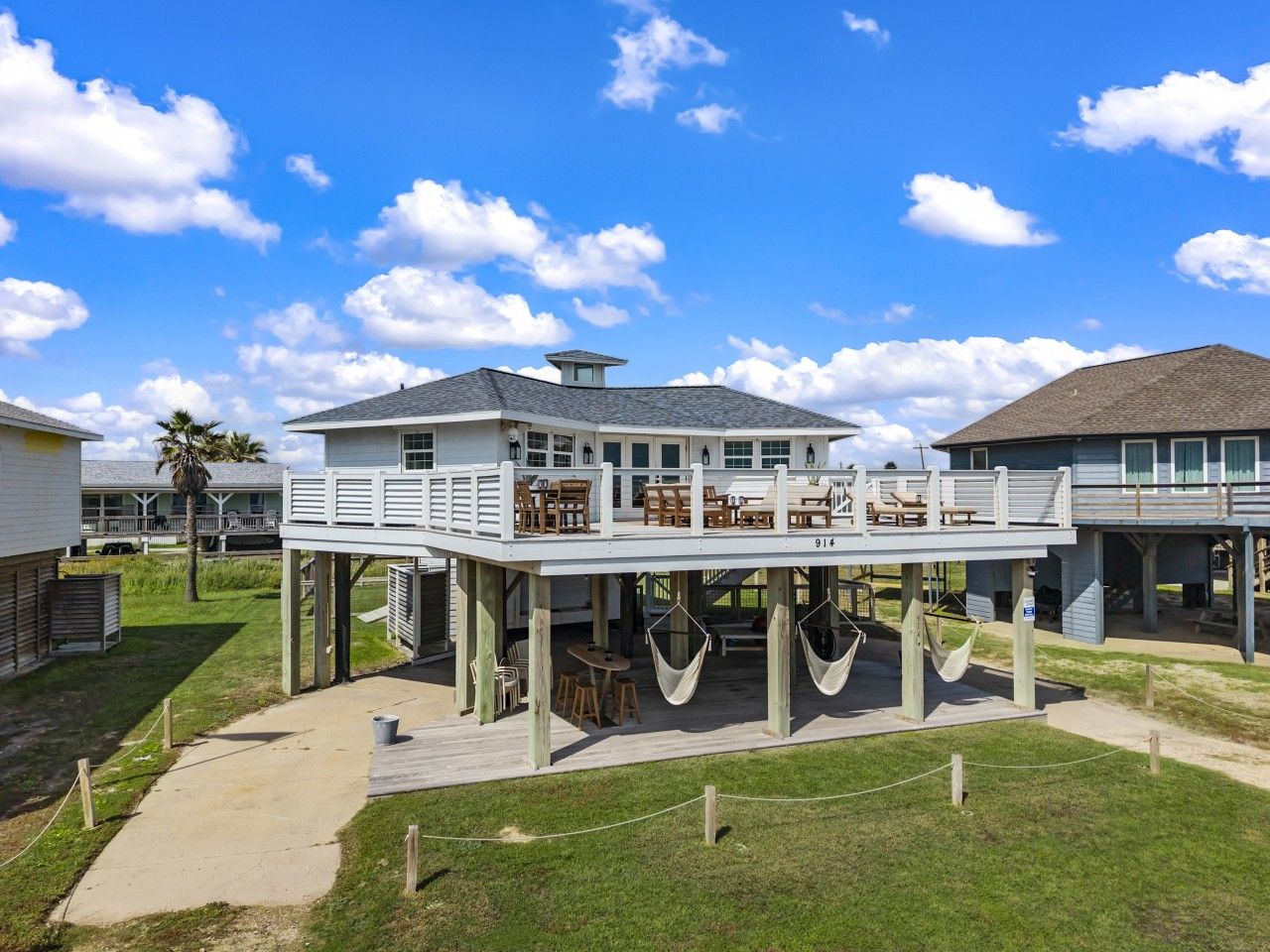 A beachfront property with a covered deck, outdoor seating, and a view of the ocean.