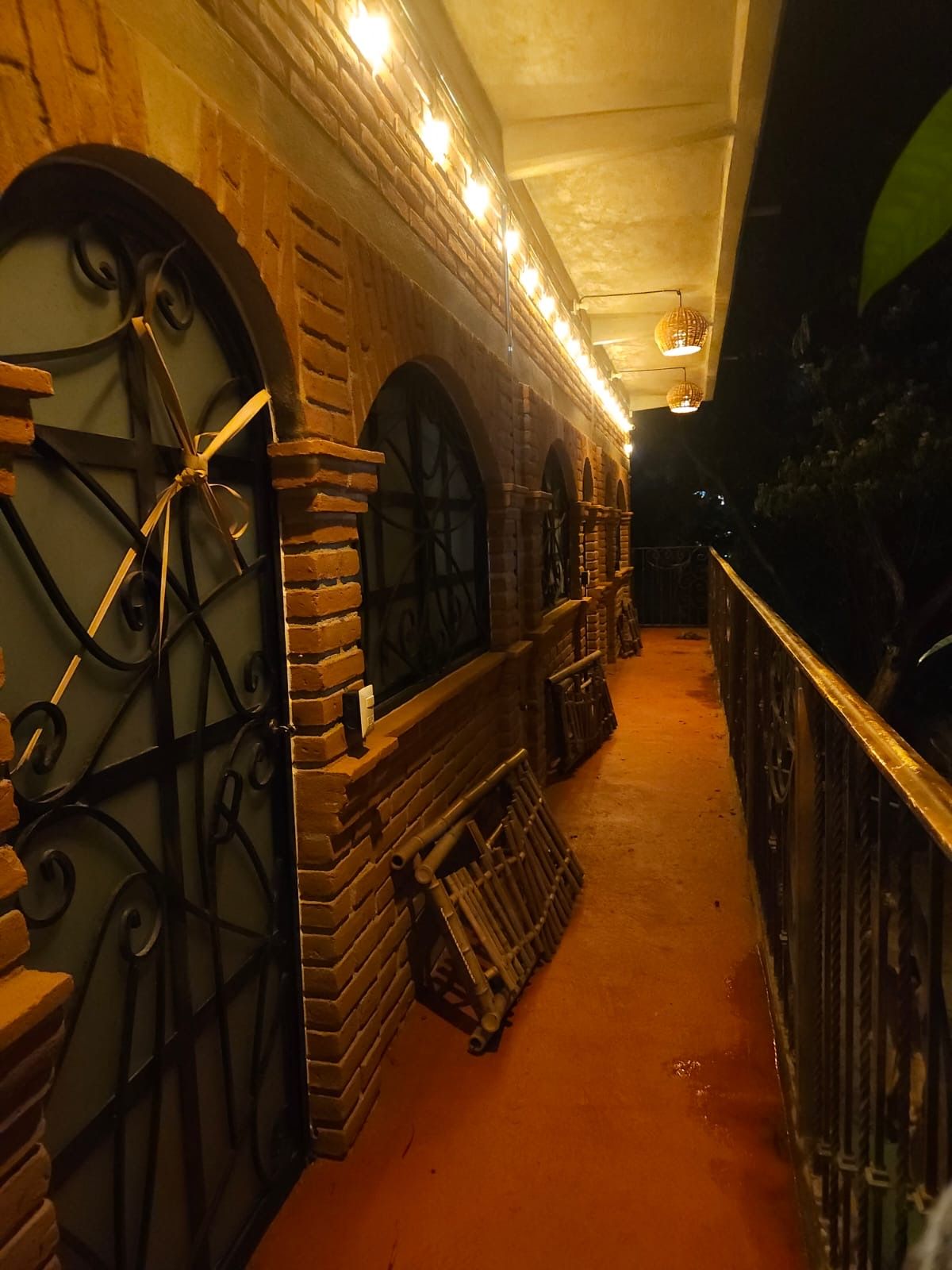 Un pasillo con paredes de ladrillo, ventanas en arco y barandillas de metal.
