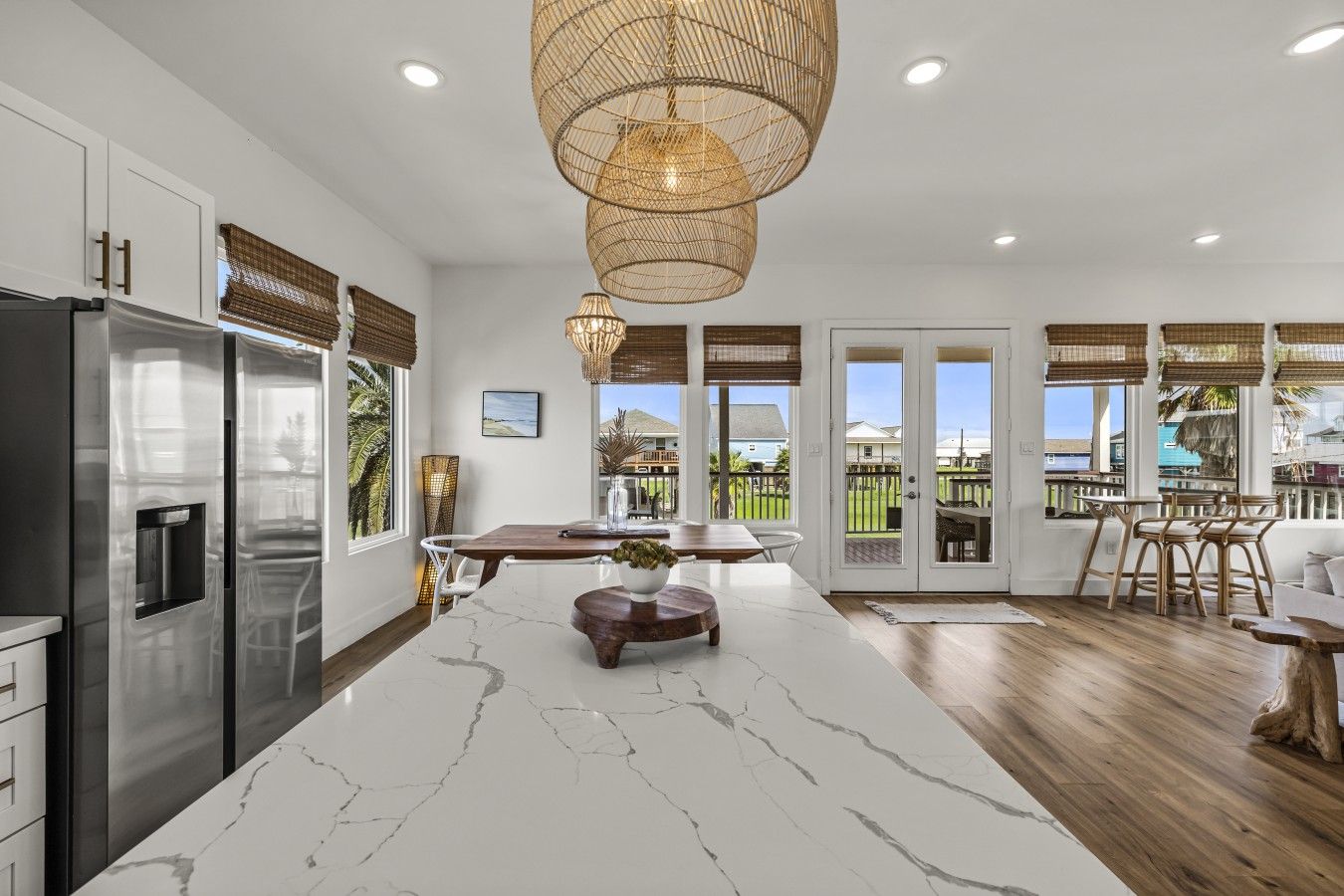 A modern kitchen with a marble island, stainless steel appliances, and a dining area with a view.