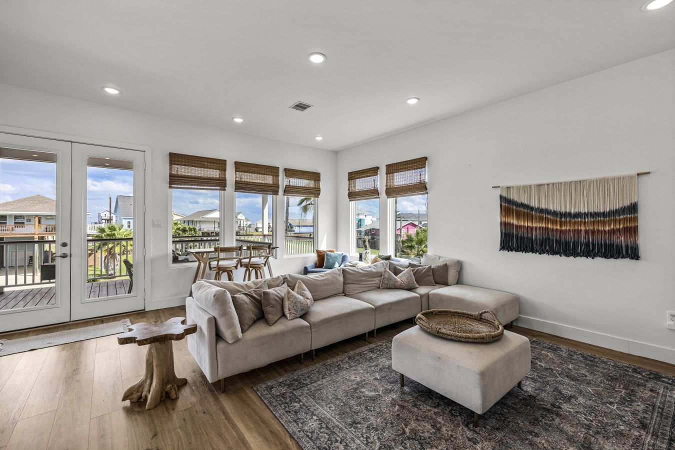 A spacious living room with a large sectional sofa, a dining area with wooden chairs, and a view through large windows.