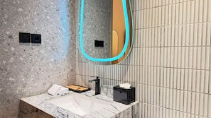 A modern bathroom with a granite countertop, a sink, a mirror, and a towel rack. - Arundra Signature Pondok Indah (Daerah Khusus Ibukota Jakarta)