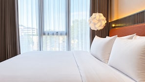 A hotel room with a large bed, a view of the city through the window, and a modern pendant light. - Arundra Signature Pondok Indah (Daerah Khusus Ibukota Jakarta)