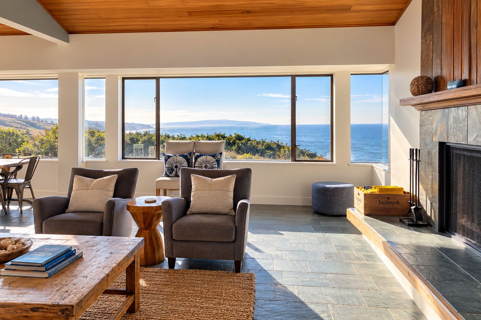 A modern living room with a fireplace, large windows overlooking a scenic view, and comfortable seating.