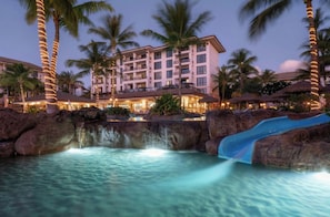 Un resort con piscina, palmeras y un edificio con varios balcones.