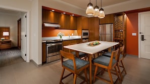 Una cocina moderna con armarios de madera, un refrigerador de acero inoxidable y una mesa de comedor con sillas.
