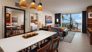 Habitación de hotel con zona de comedor, sofá, balcón con vistas y un espejo grande.