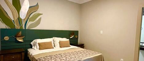 A bedroom with a bed, nightstands, a dresser, a mirror, and a wall with a leaf design.