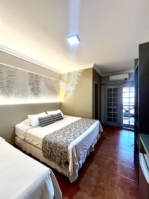 A hotel room with two beds, a flat-screen TV, and a ceiling light.