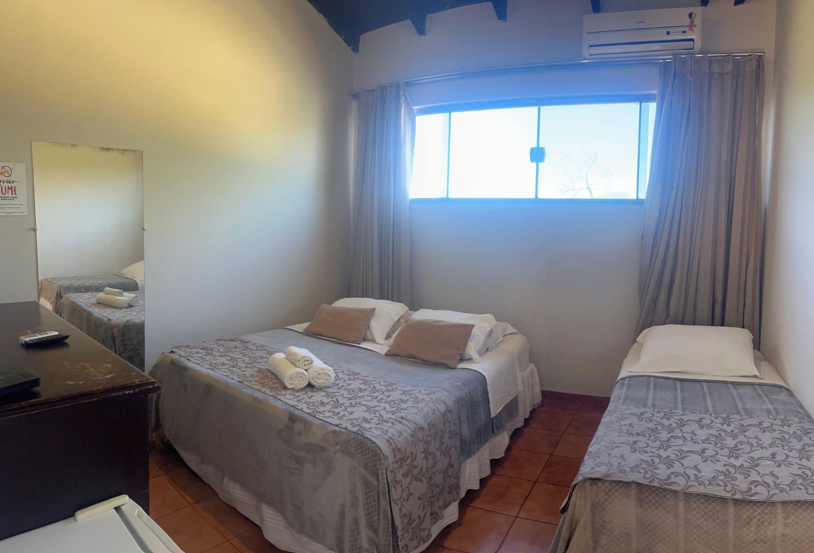 A hotel room with two beds, a desk, and a window with curtains.