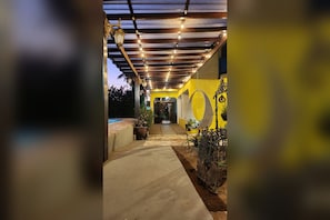A covered outdoor area with a concrete pathway, potted plants, and hanging lights. - Pousada Villa Guimarães  (CHAPADA DOS GUIMARÃES)