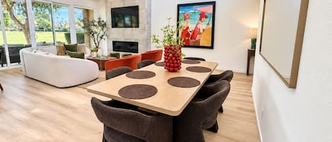 A modern dining area with a wooden table, dark chairs, and a white sofa.