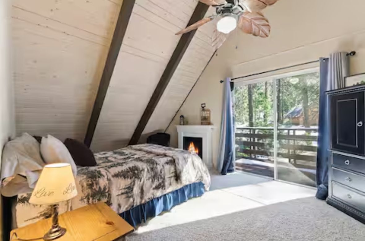 Una camera da letto con un letto, una lampada, un camino e vista sull'esterno.