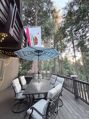 A deck with a table and chairs, surrounded by a wooden railing, and a flag with a bear emblem.