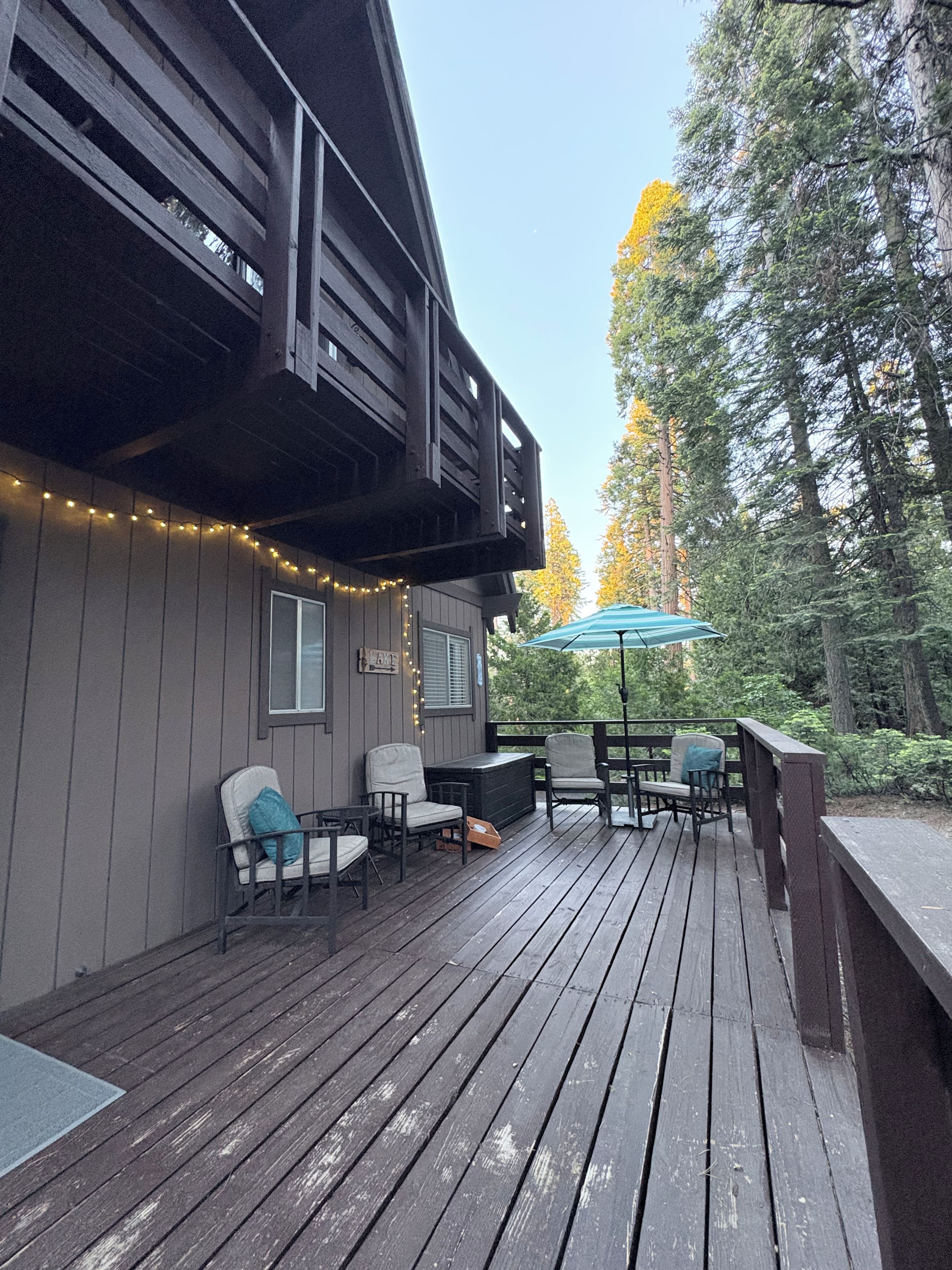 A wooden deck with outdoor seating and string lights.