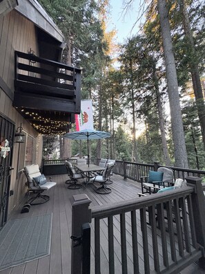 A wooden deck with outdoor furniture, a table, and an umbrella.