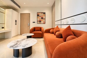 A modern living room with a sofa, two side tables, and a wooden door. - Hotel Vedantra (Bikaner)