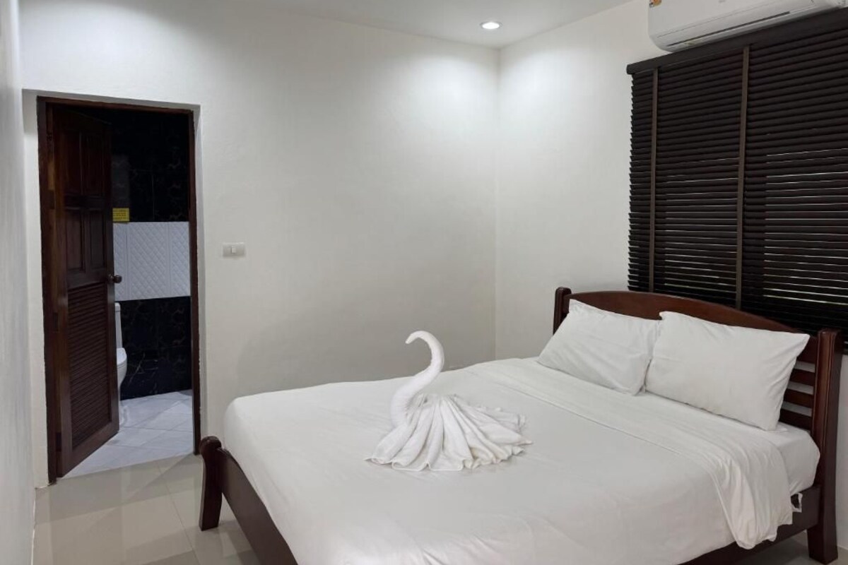 Een hotelkamer met een bed, een deur en een raam met jaloezieën.