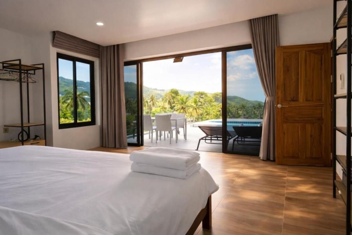 Een hotelkamer met een groot bed, uitzicht op de omgeving, een zithoek en een houten deur.
