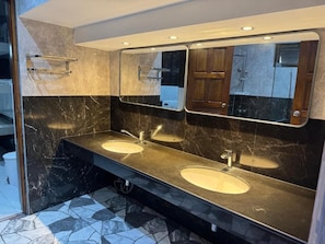 Een moderne badkamer met twee wastafels, een grote spiegel en een douche.