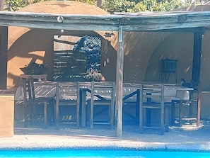Ein Poolbereich mit überdachter Sitzgelegenheit, einem Tisch und einem Stuhl.