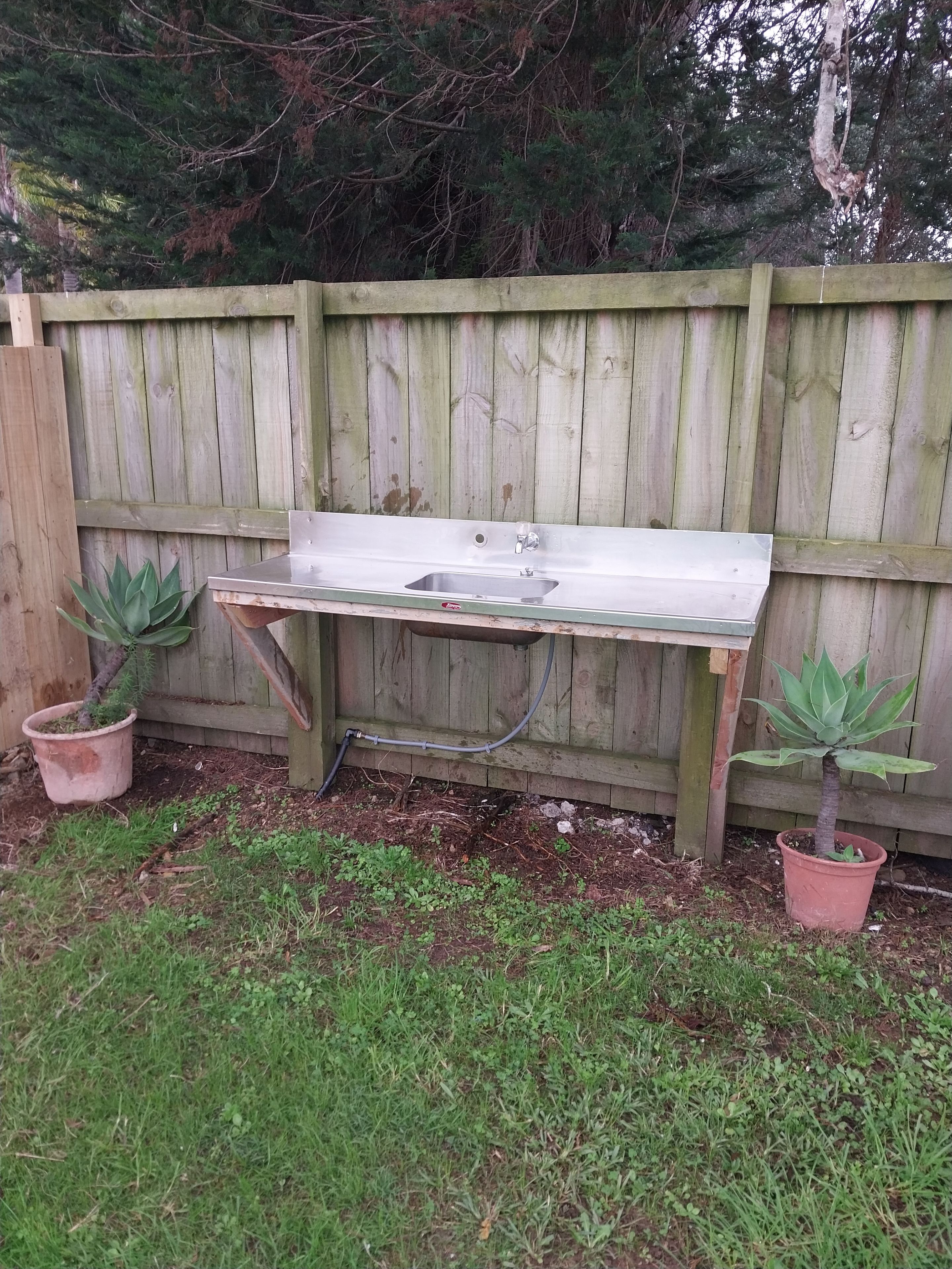 A wooden fence with a metal sink attached to it.
