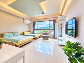 Habitación de hotel con dos camas, televisor, balcón y vistas al exterior.