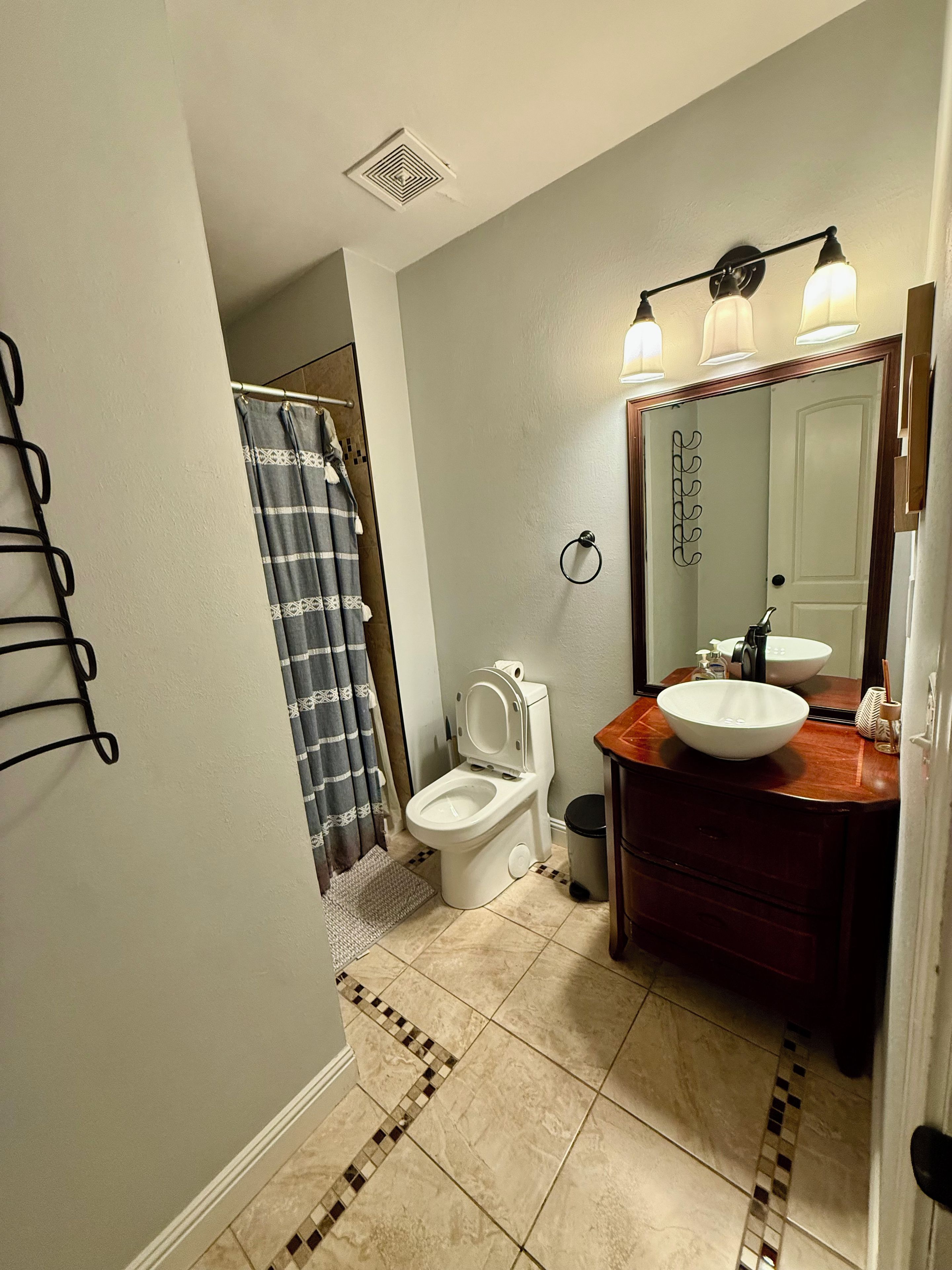 Et badeværelse med toilet, håndvask og badeforhæng.