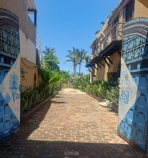 Un chemin pavé mène à un bâtiment sur lequel est apposée une enseigne indiquant « Casa Varuna ».