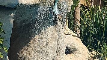 Une statue représentant une sirène assise sur un rocher, au bord d’une piscine.
