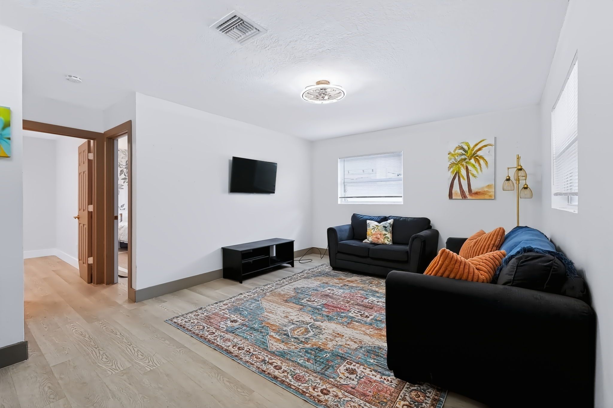A modern living room with a black sofa, a patterned rug, and a flat-screen TV.