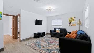 A modern living room with a black sofa, a patterned rug, and a flat-screen TV.