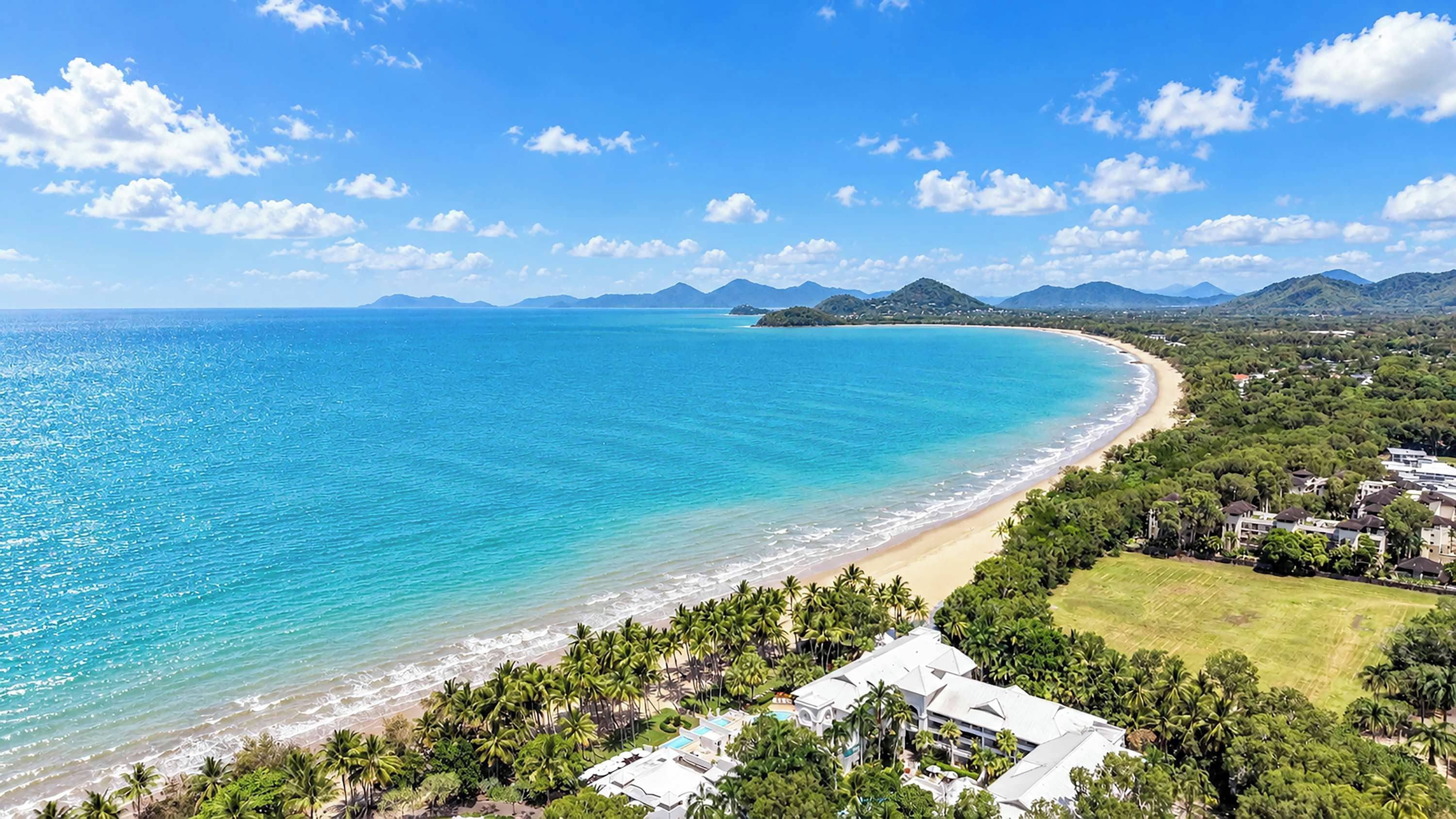 A coastal resort with a beachfront, palm trees, and a view of the ocean.