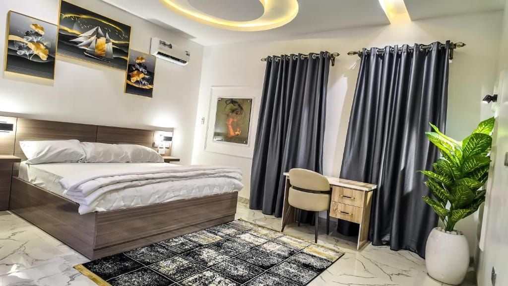 Ein modernes Hotelzimmer mit Bett, Schreibtisch, Stuhl und einer Zimmerpflanze.