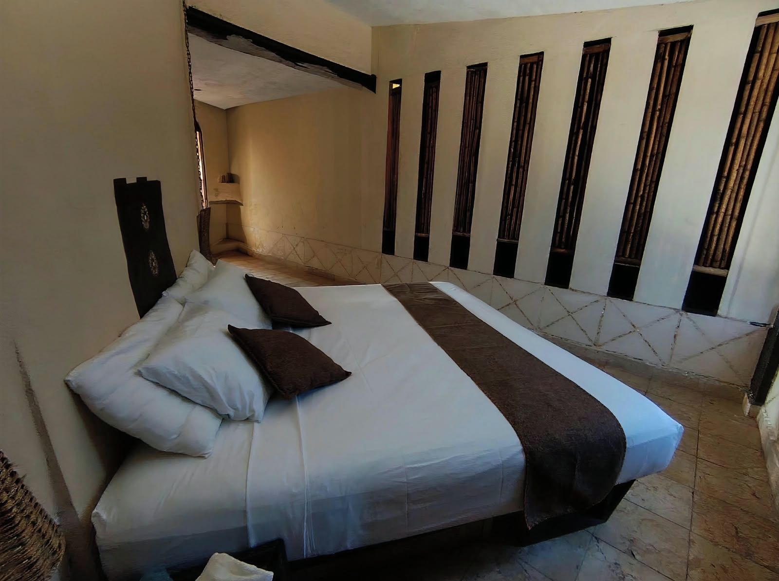 Een hotelkamer met een groot bed, een nachtkastje en een raam met verticale jaloezieën.