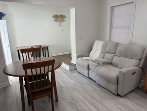 Un salon avec un canapé gris, une table à manger en bois et des chaises.