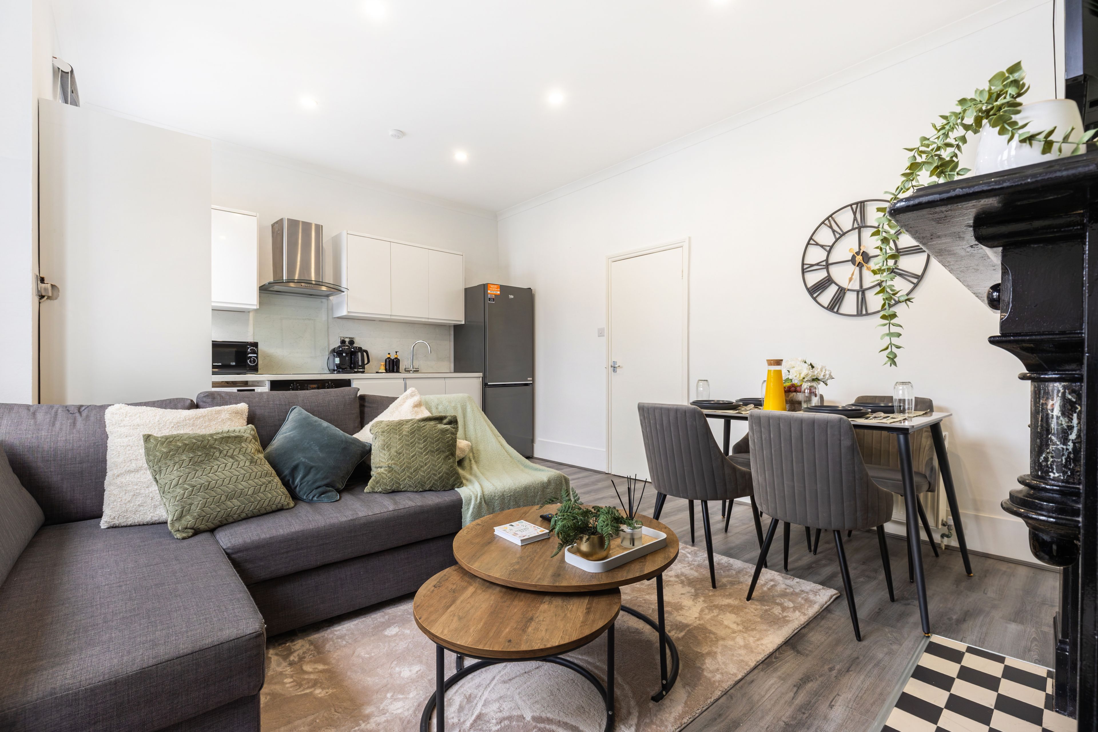 A modern living room with a grey sofa, a coffee table, and a dining area with chairs and a table.