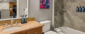 A bathroom with two sinks, a toilet, a shower, and a large mirror. - 2BR Deluxe Suite Steps from F1 Grand Prix Plaza - Race Weekend (Las Vegas)