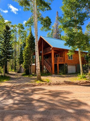 A wooden cabin with a porch, surrounded by trees. - Mountain View Hideaway (Brian Head)