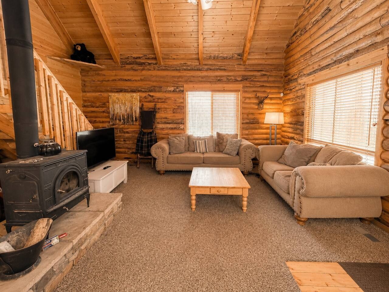 A log cabin interior with a fireplace, sofa, and television.