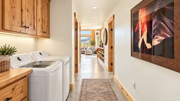 A laundry area with a washing machine and dryer, wooden cabinets, and a large framed artwork on the wall.