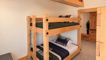 A bunk bed with a wooden frame and a desk in a room with a sloped ceiling and wooden beams.