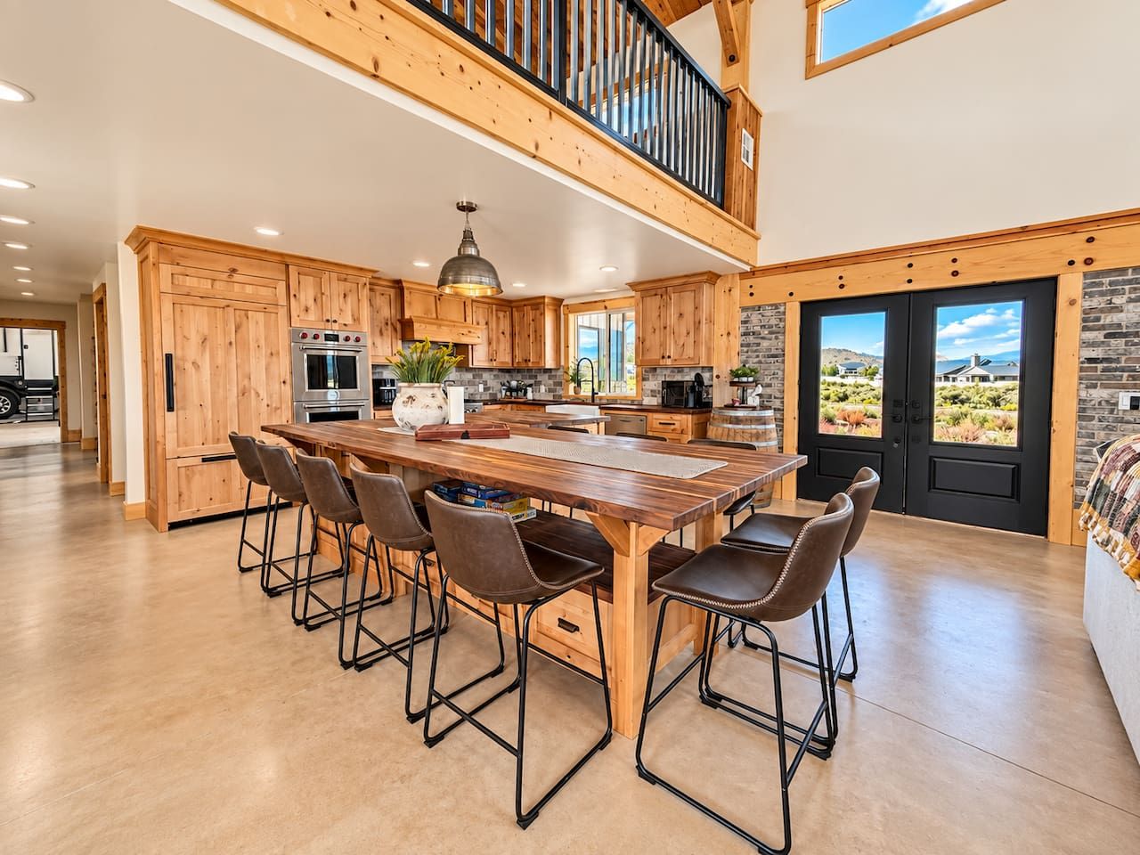 A spacious kitchen with a large island, wooden cabinets, and a view to the outside.
