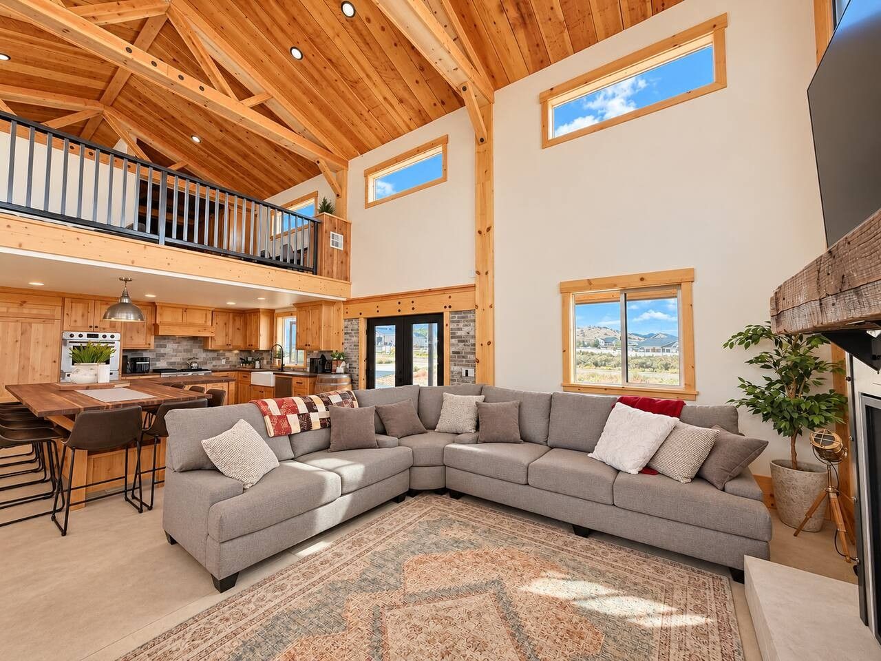 A spacious living area with a large sectional sofa, a dining table, and a kitchen in the background.