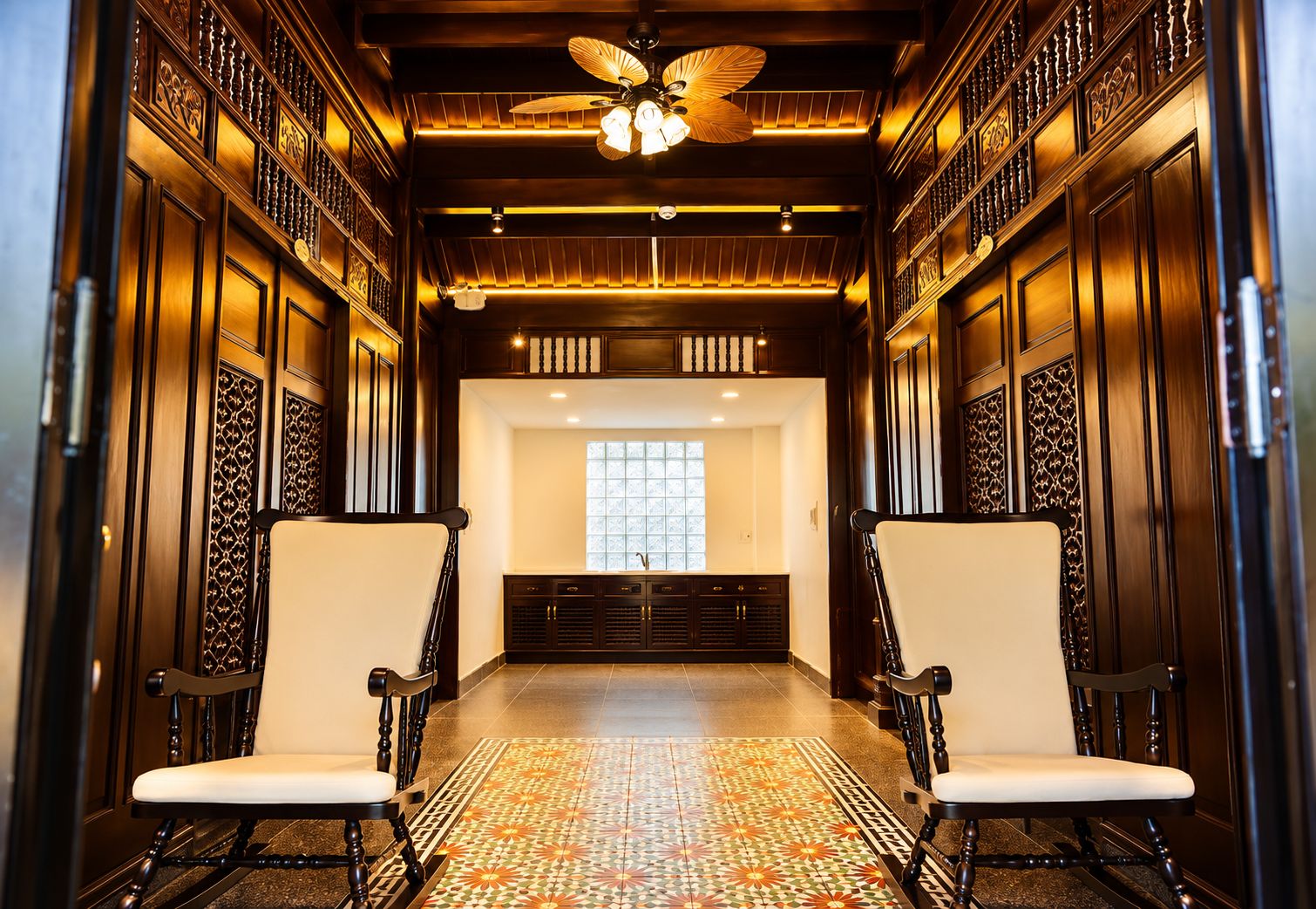 A hallway with two chairs, a patterned floor, and a ceiling fan.