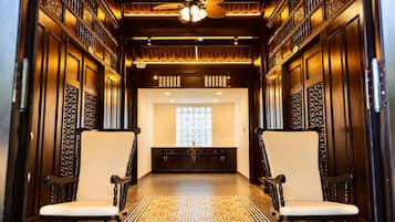 A hallway with two chairs, a patterned floor, and a ceiling fan.