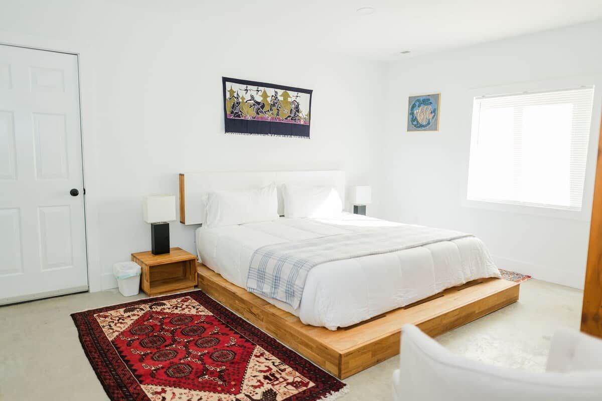 Une chambre à coucher avec un lit, des tables de chevet, un tapis et des œuvres d’art accrochées aux murs.